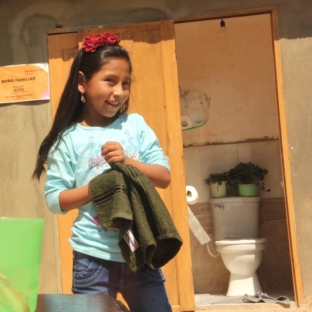 A girl washing her hands outside of a newly build toilet facility 