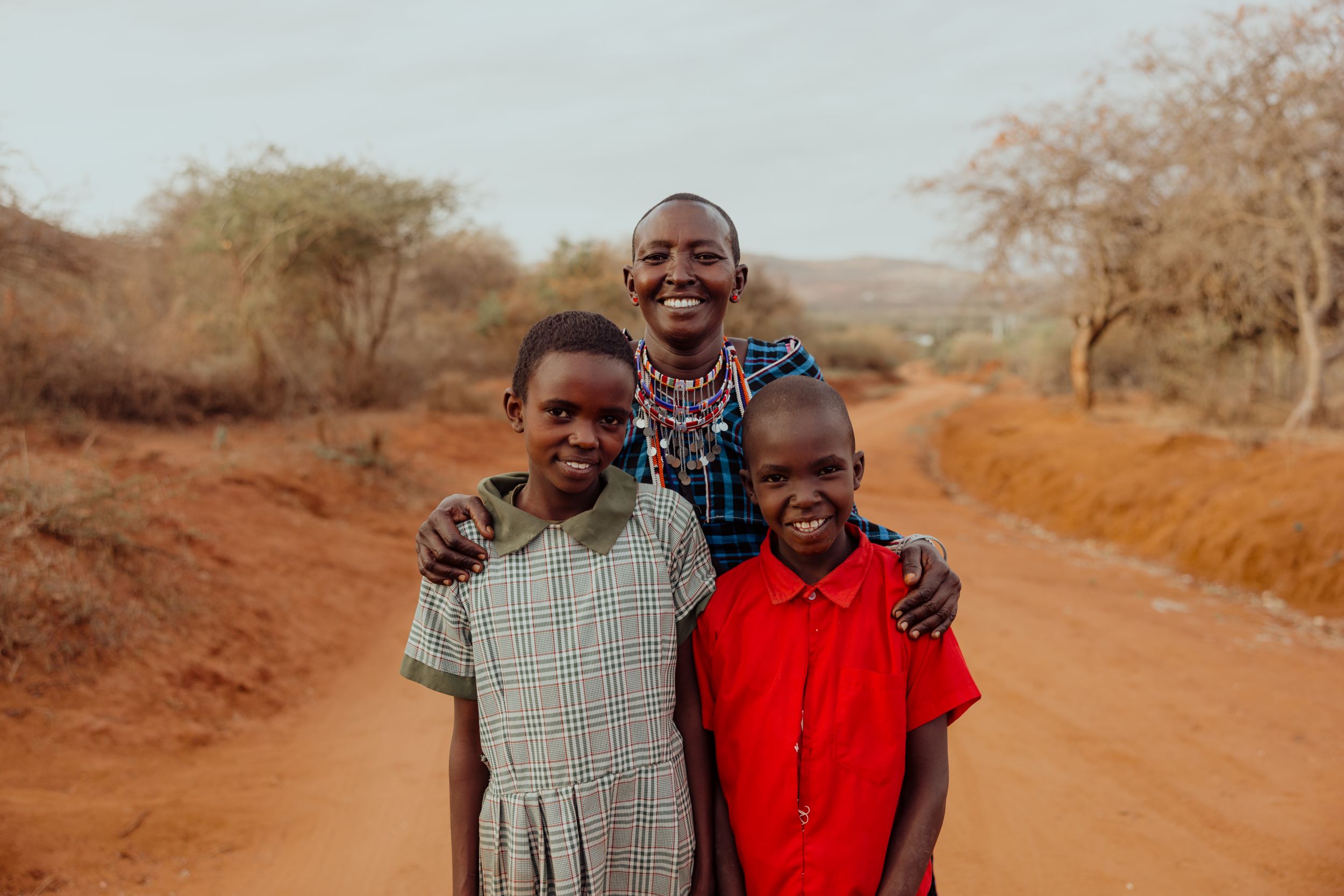 Kenyan woman in blue check traditional dress poses with her daughter and son