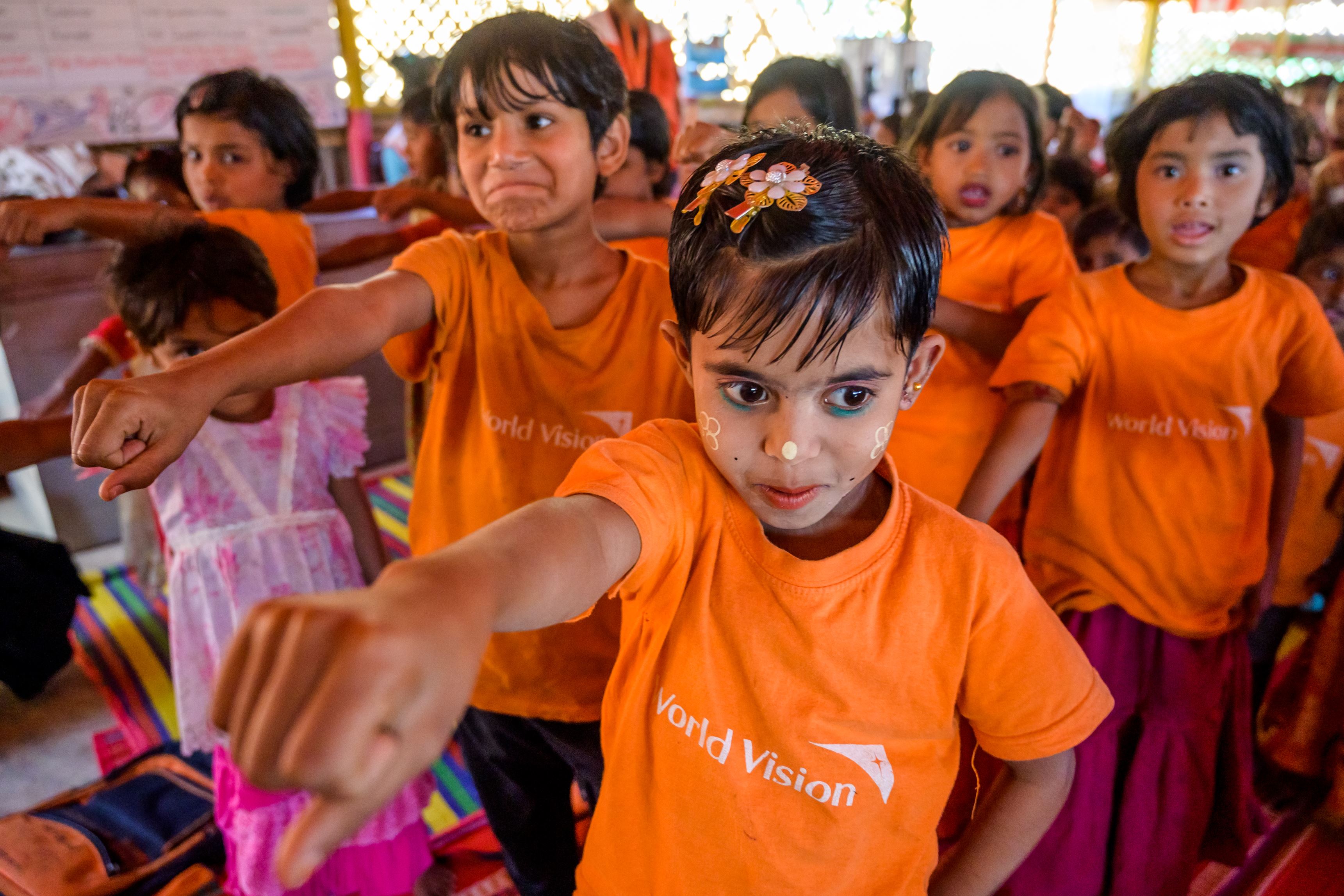 Rohingya children in orange World Vision tshirts posing powerfully in a Child Friendly Space in a refugee camp in Bangladesh