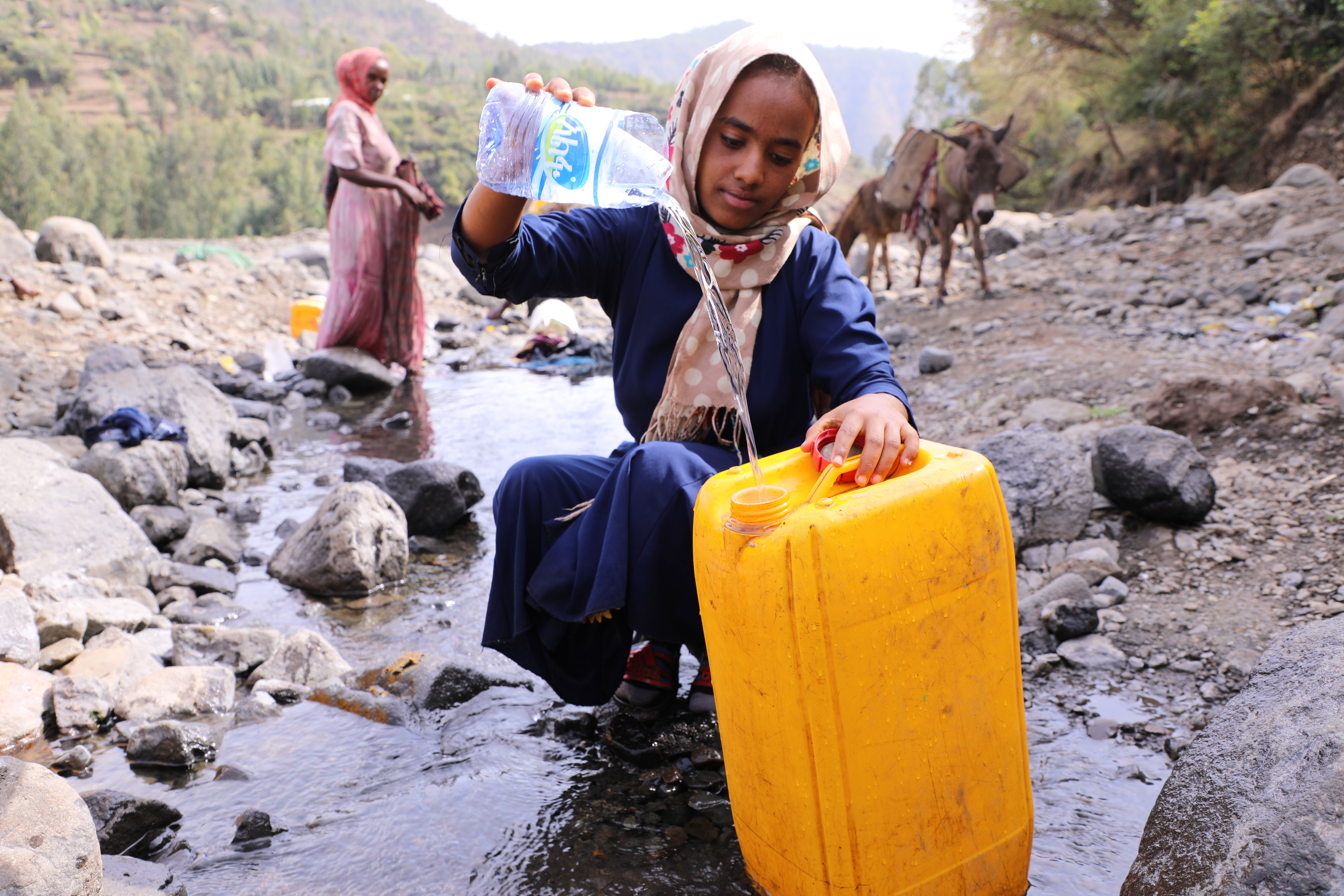 Girl from Ethiopia pours water into a bucket