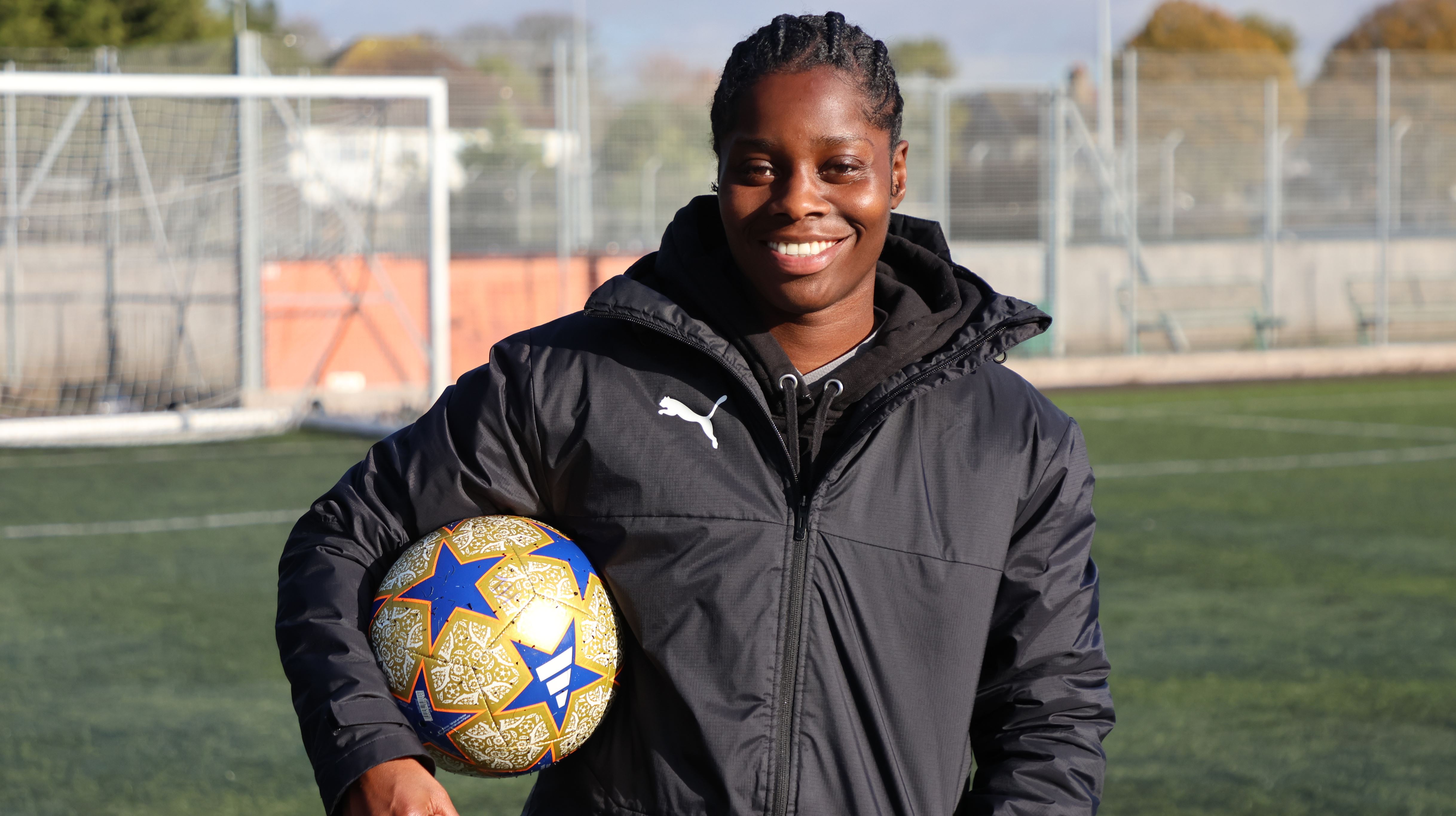 Freda Ayisi smiles whilst holding a football under her arm