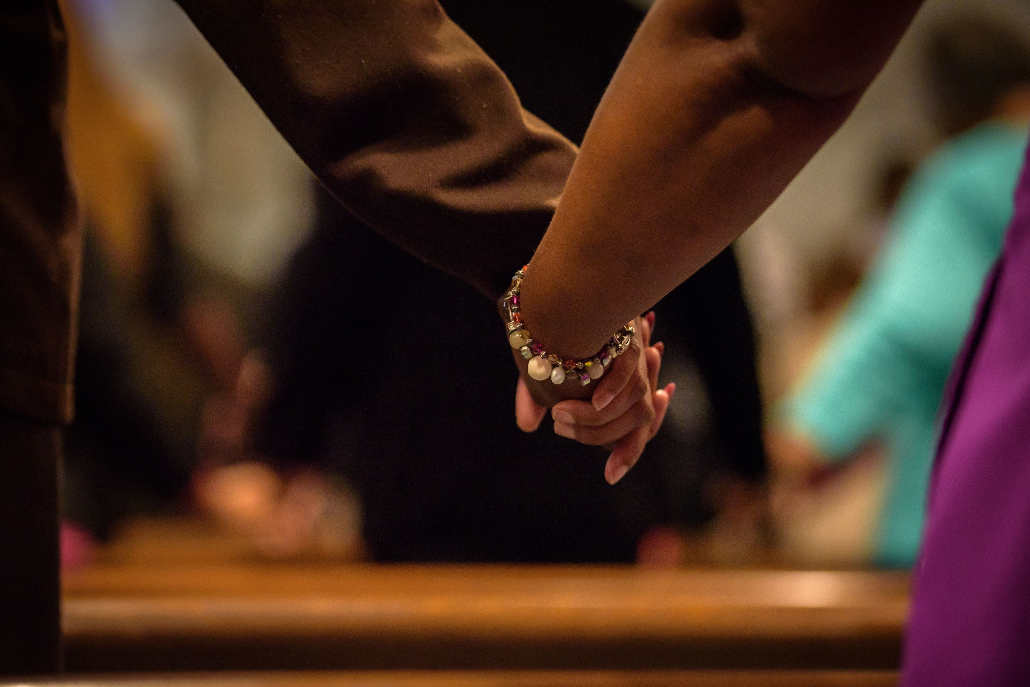 Two people in the US stand with hands entwined in a church