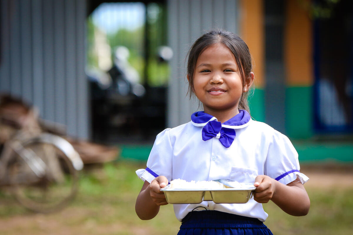 Cambodian girl wearing school uniform and holding a tray of food