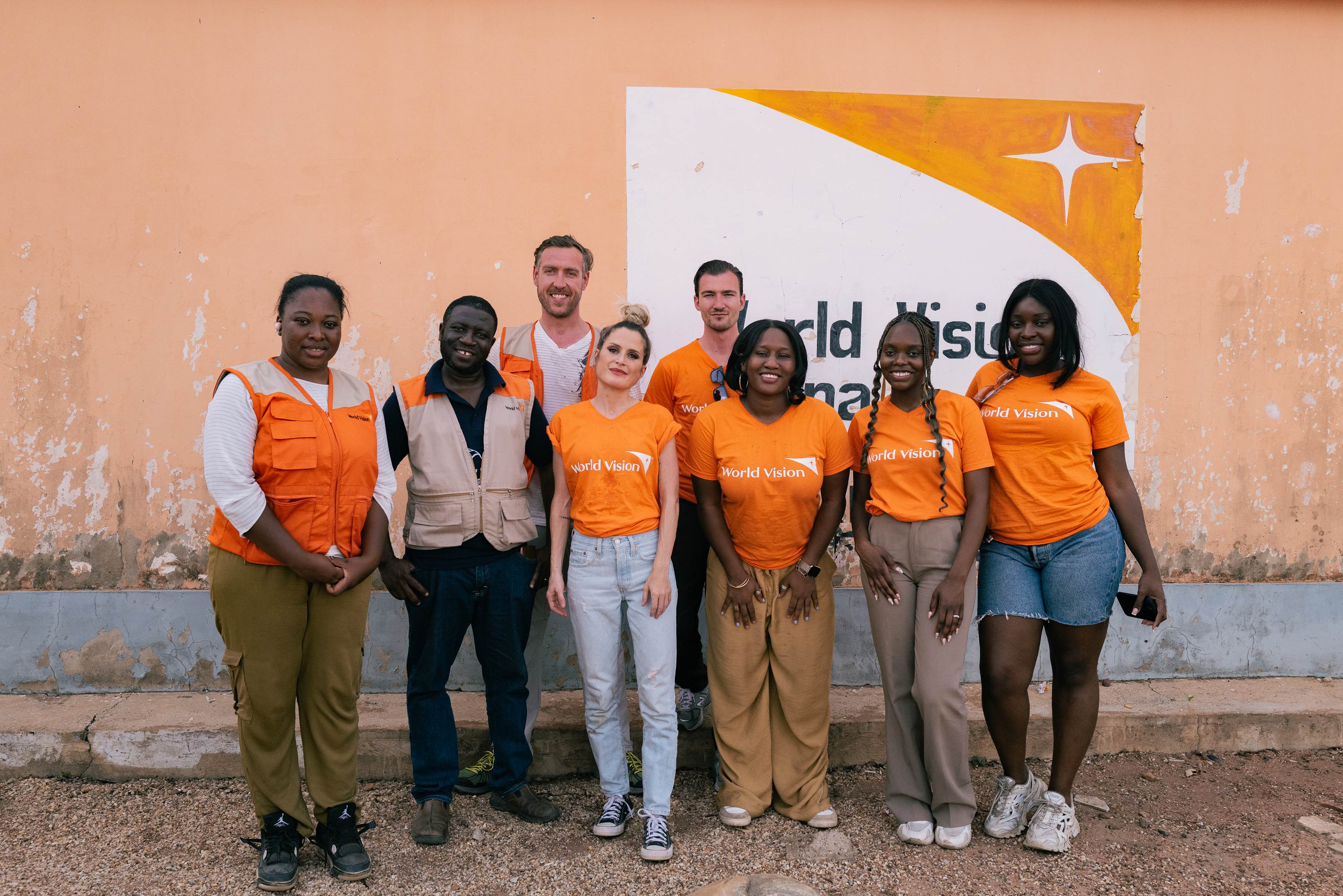 Brett and fellow creators smile at camera in front of World Vision background