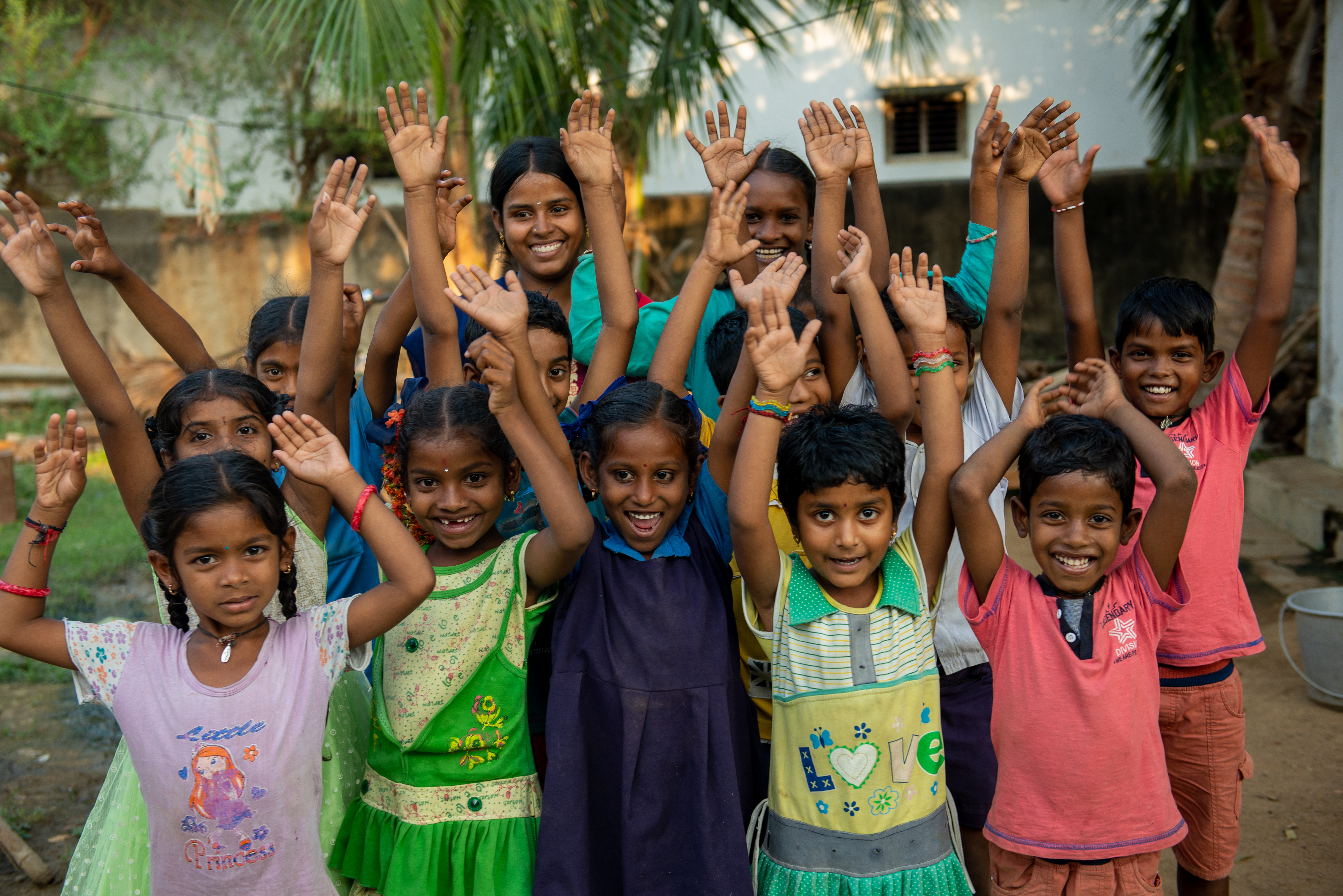 Group of children smiling with hands in air