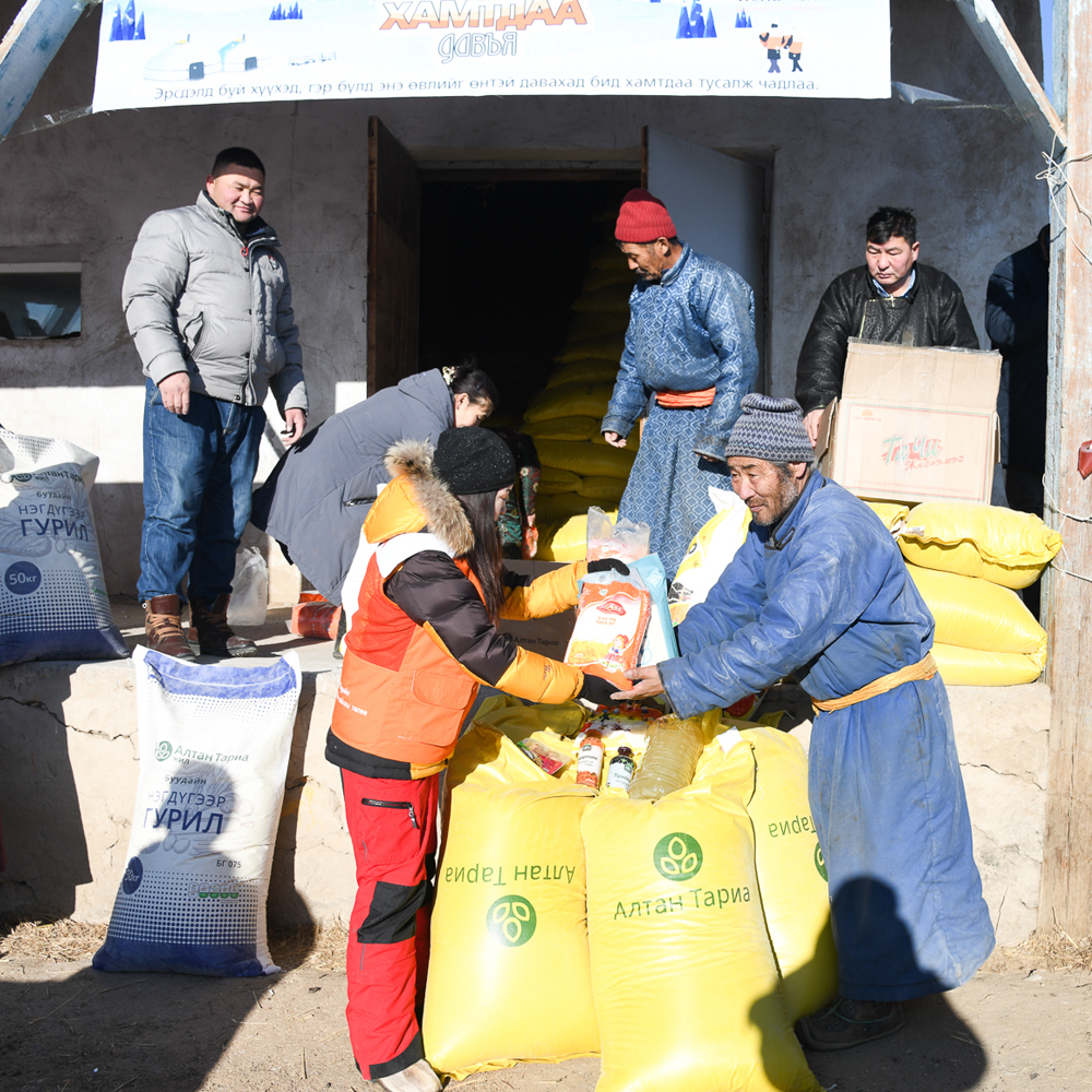 World Vision worker handing large bags of food to community