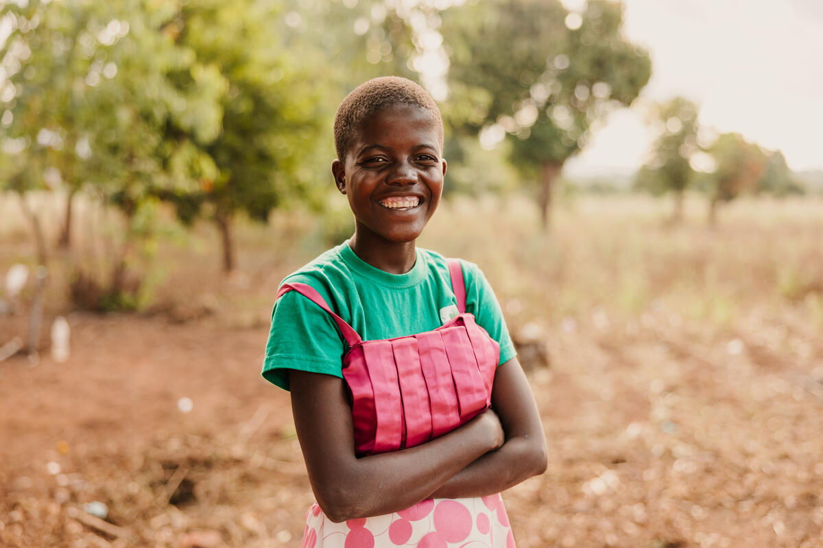 12 year old girl in Malawi smiling with arms crossed