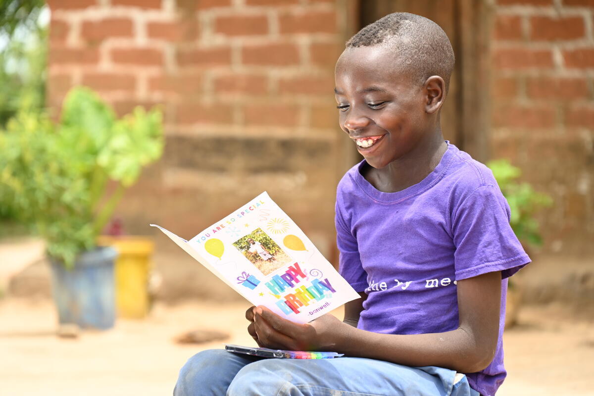 A young sponsored boy in Zambia reads a birthday card from their sponsor