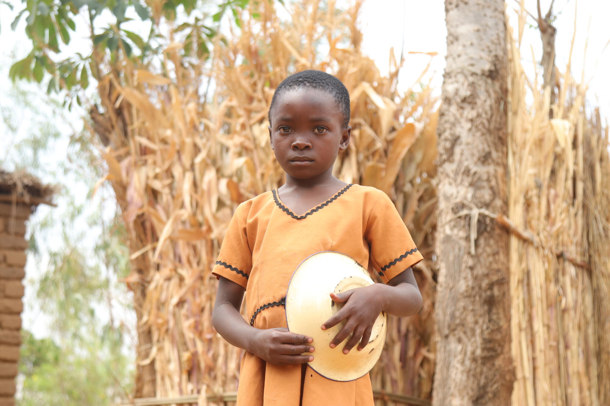 A girl in Malawi looks pensive holding a plate