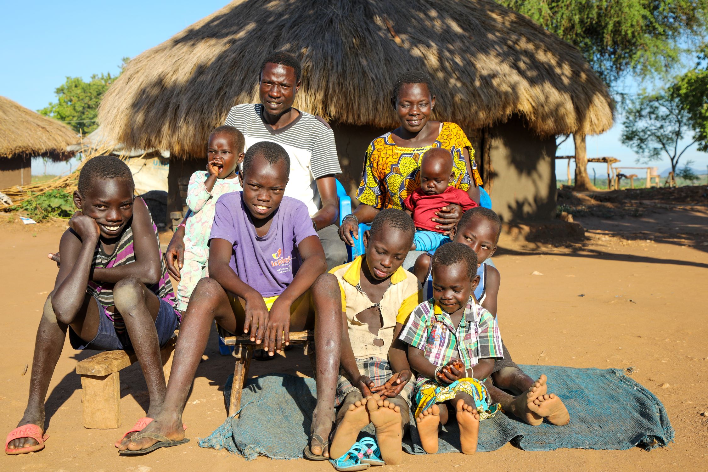Mustafa (purple shirt-striped) with his family in Uganda refugee settlement.