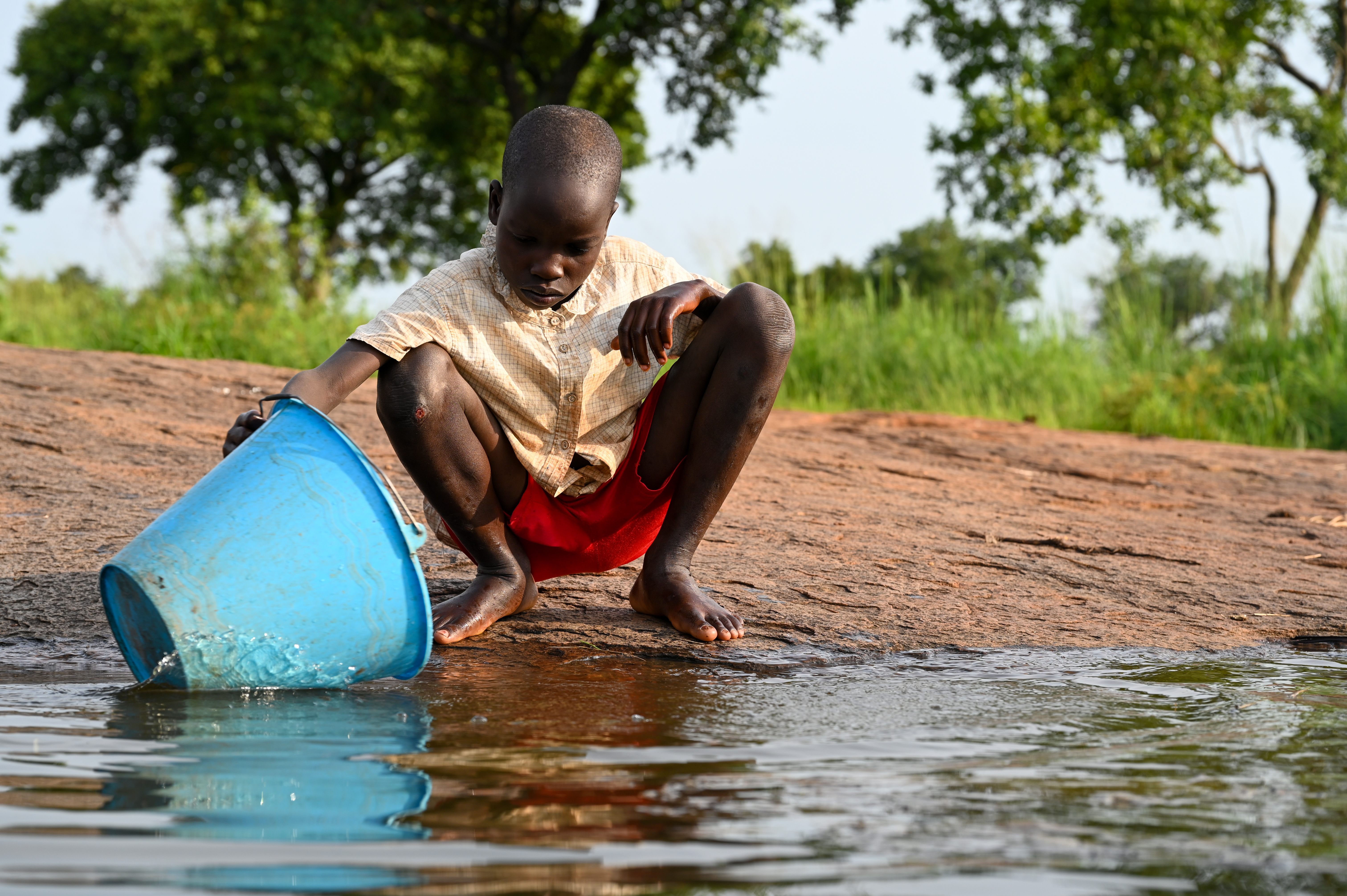 A boy in Uganda collecting dirty water