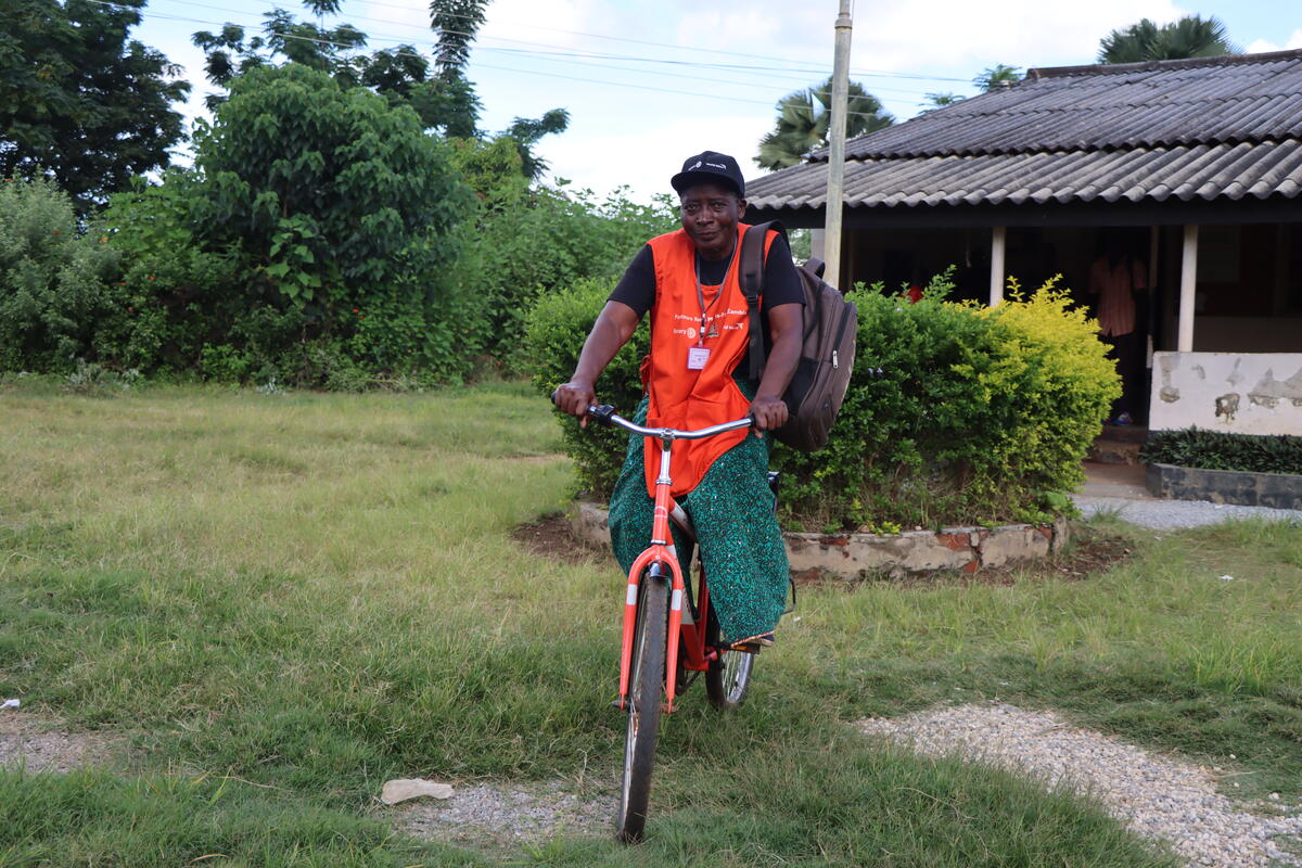 Zambian community health worker rides her bike to the medical post