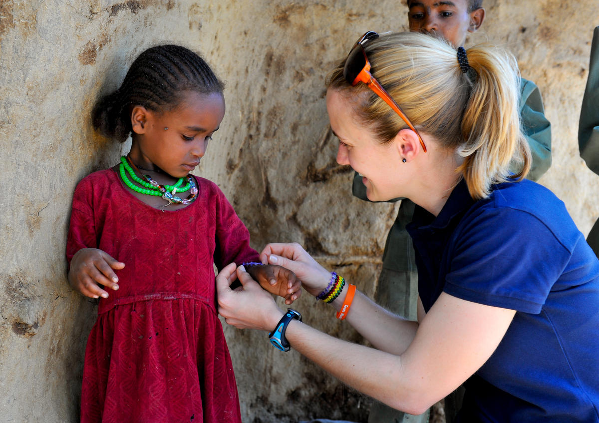A child sponsor, gives a girl a necklace and bracelet matching her own, in Ethopia.