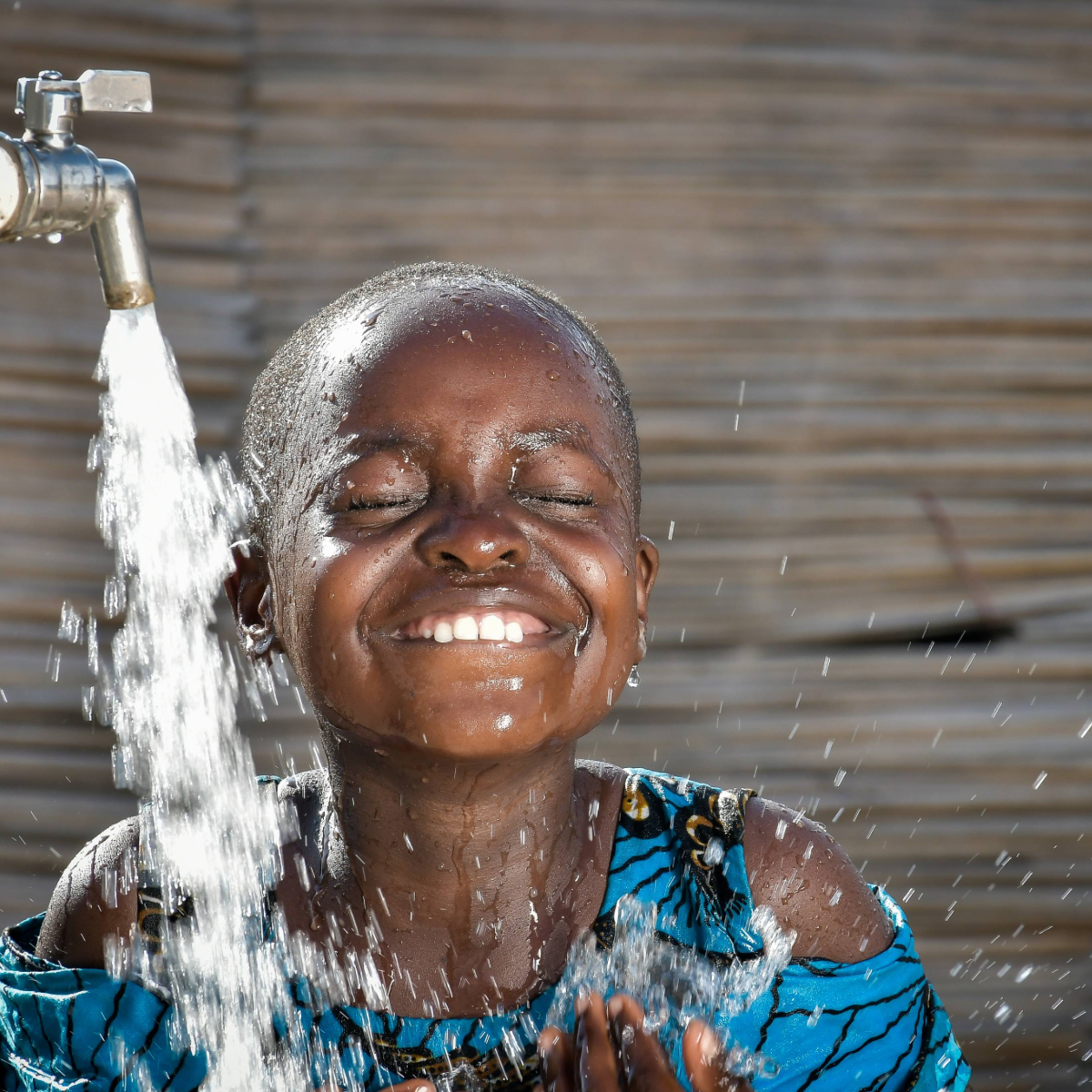 A young girl in Ghana enjoying clean water from a tap