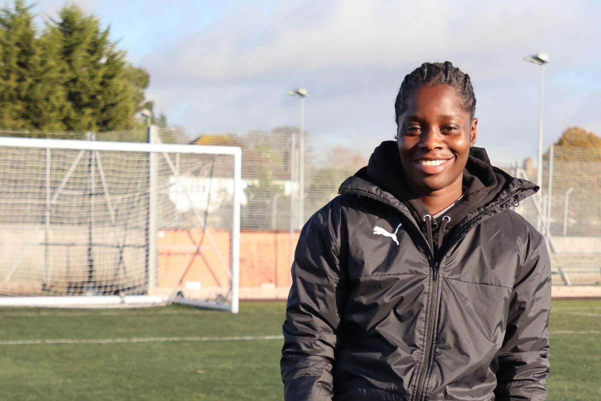 Freda Ayisi smiles whilst holding a football under her arm
