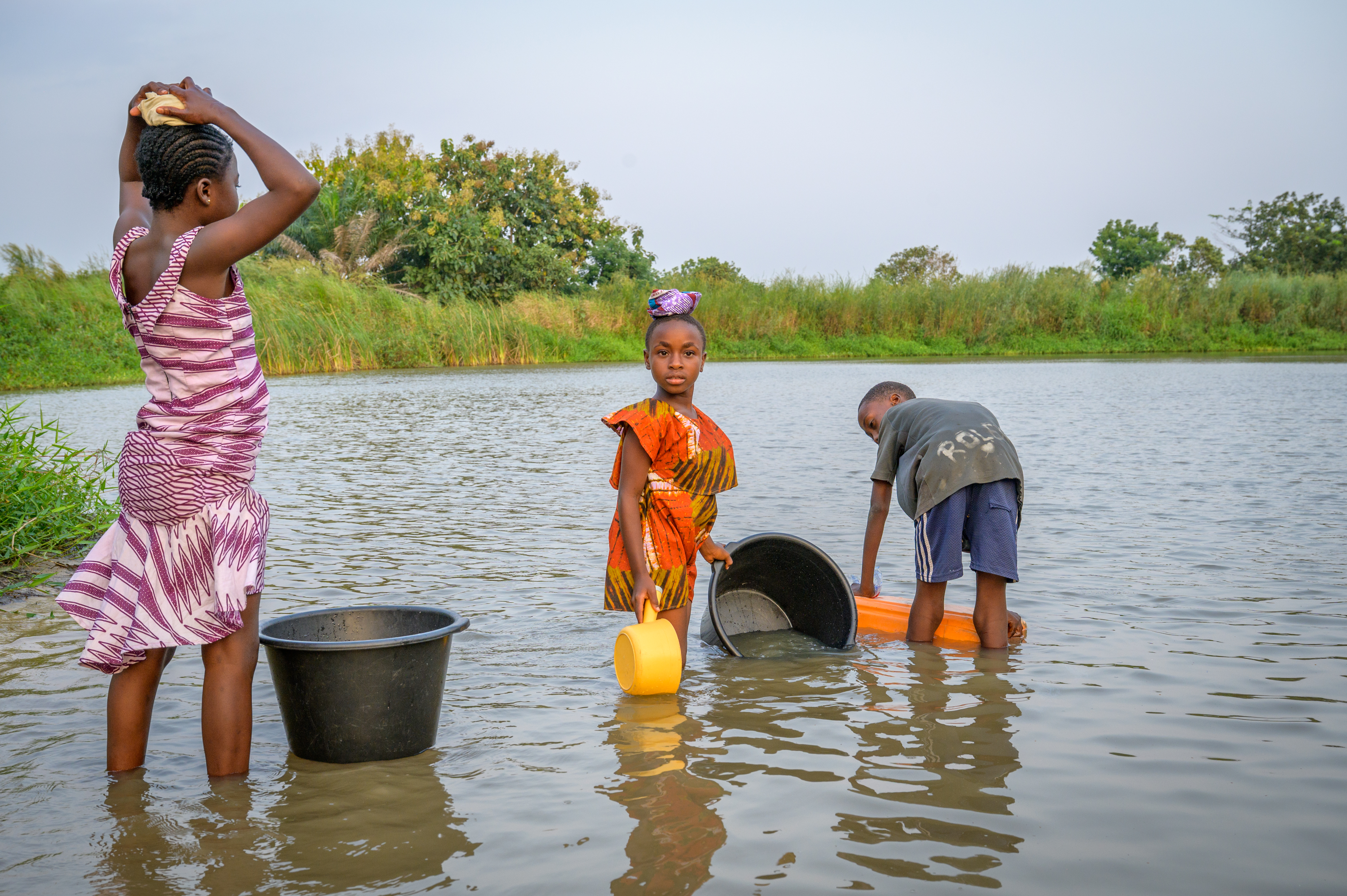 Children collect water in buckets from a lake