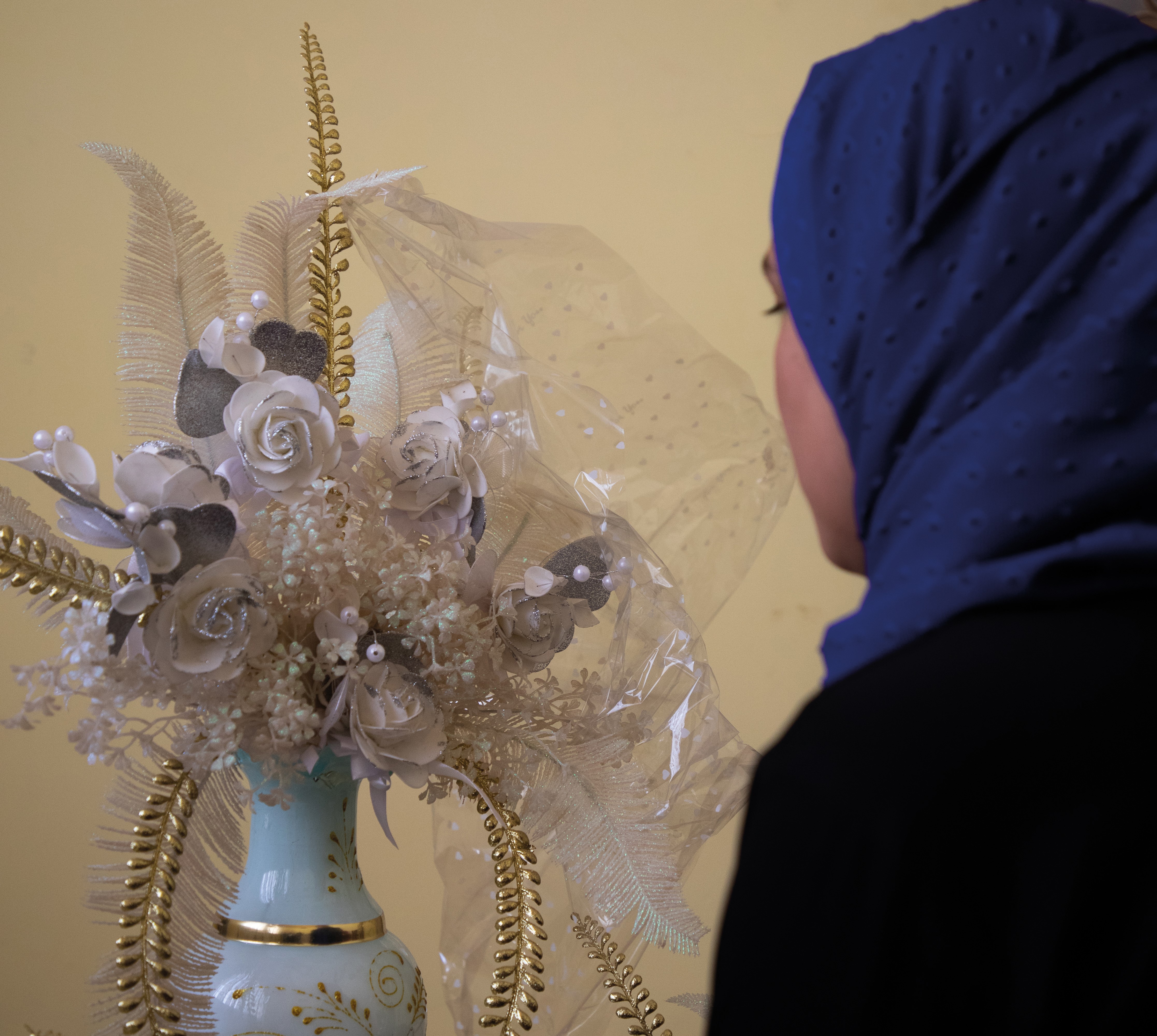 Girl in Afghanistan looks away from the camera towards flower decorations prepared for her child marriage