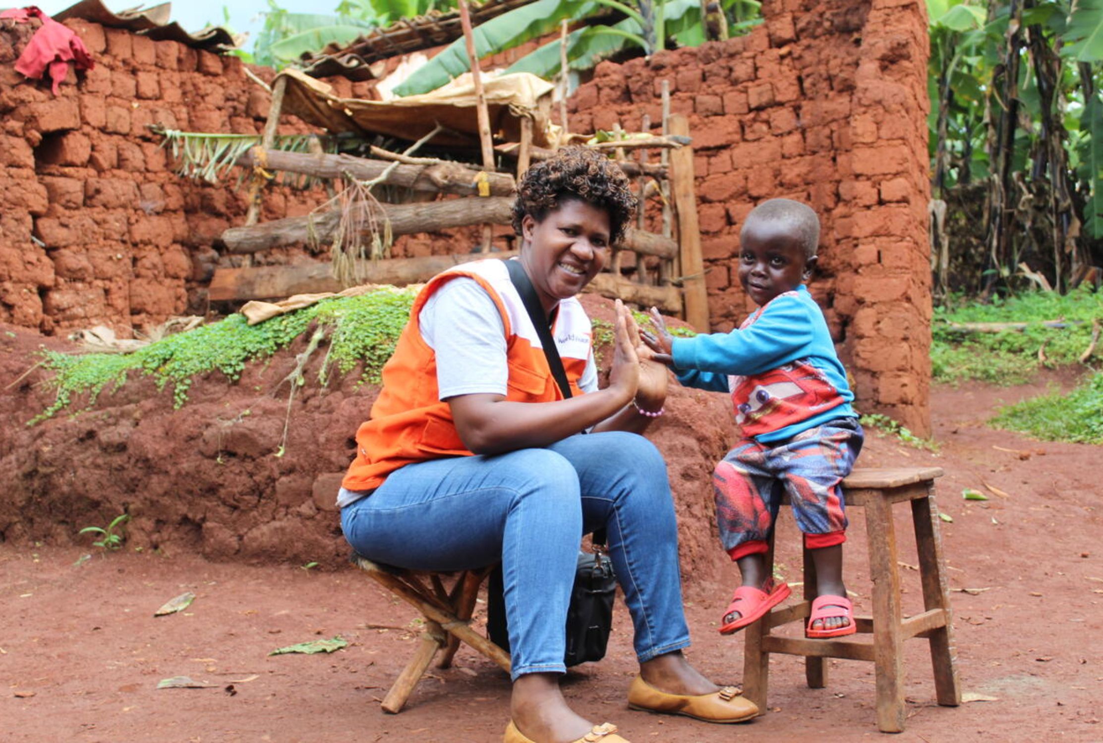 World Vision staff member sat with a smiling child in Burundi