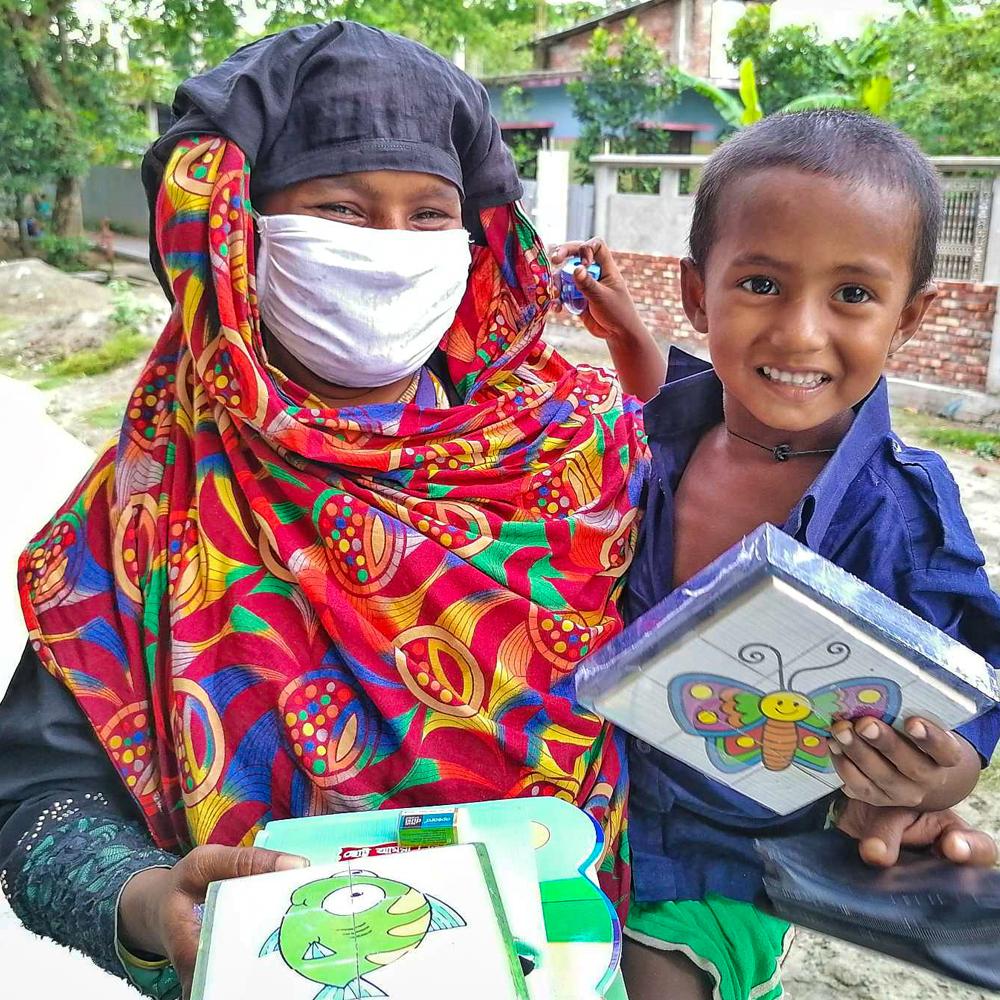 A woman in a mask holding a child and various activity packs