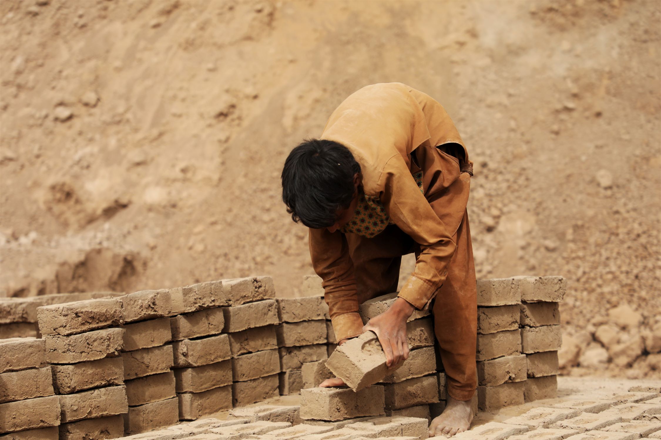 Boy lifting bricks in Afghanistan