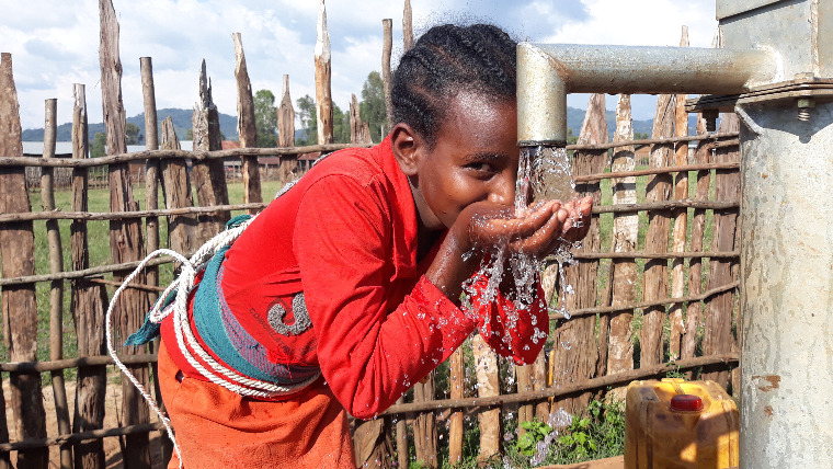 Girl from Ethiopia drinking clean water from a tap.