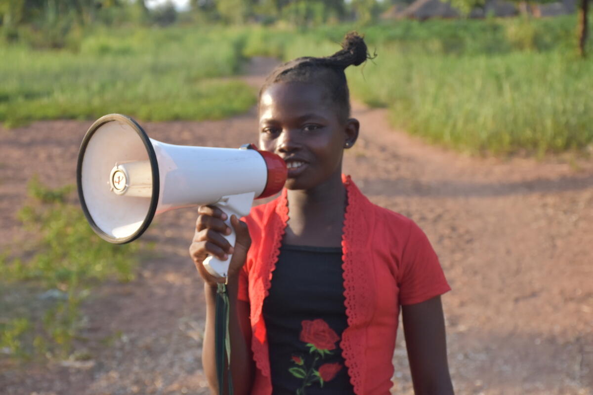 Priscillia, 12, uses a megaphone to share protection messages with her community