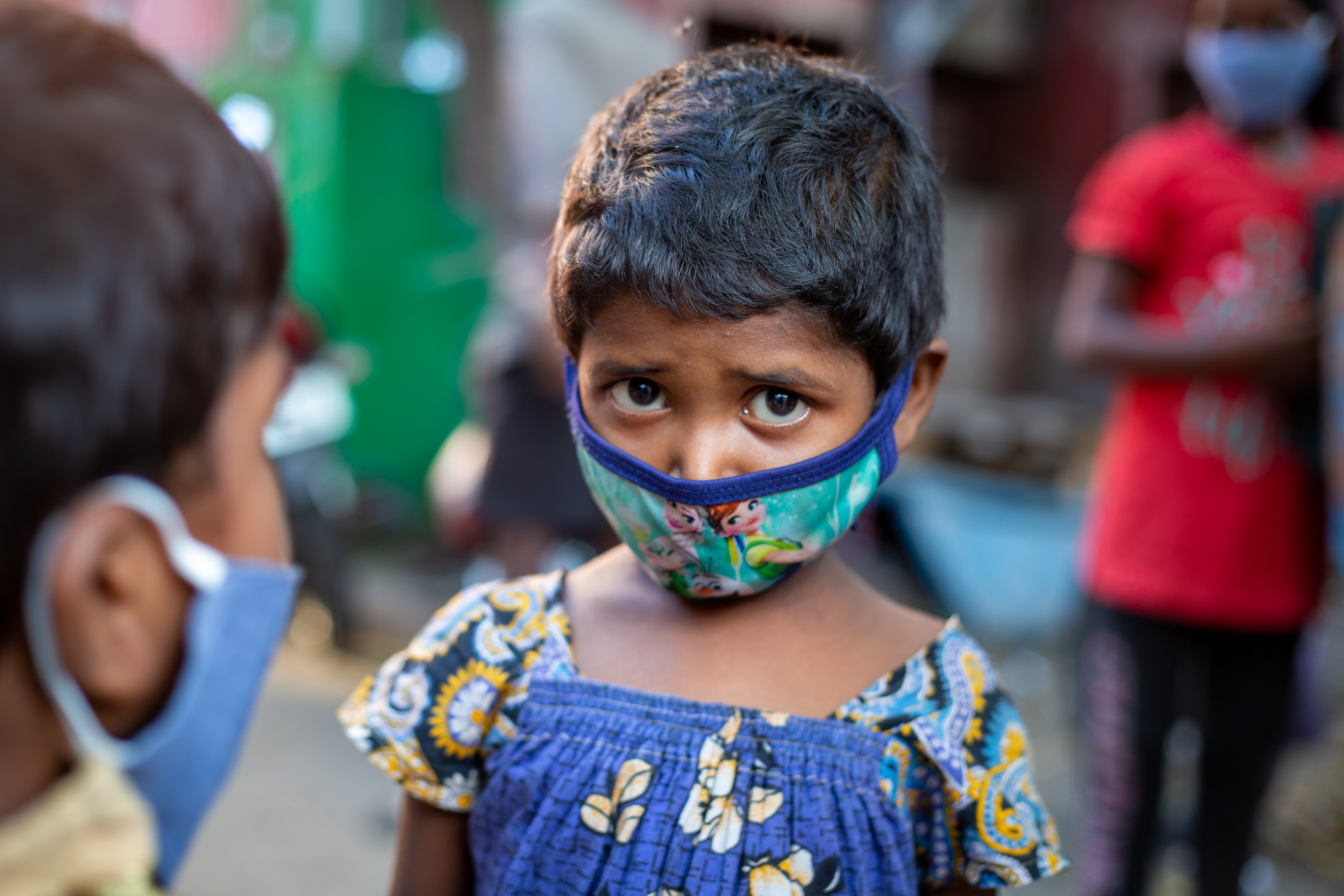 A girl from Chennai, India, with a mask covering her face, looks to the camera.