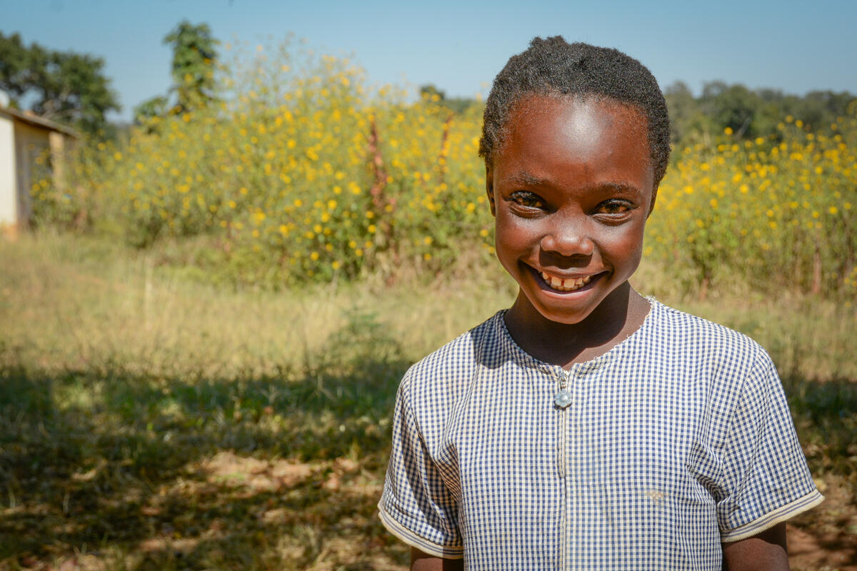 Former sponsored child smiles in field in Zambia