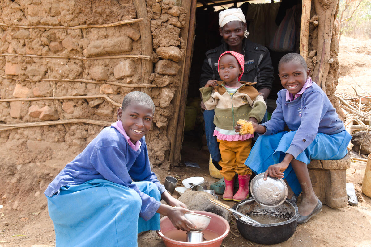 Anastacia from Kenya and her daughters wash dishes after eating a small ration of maize.
