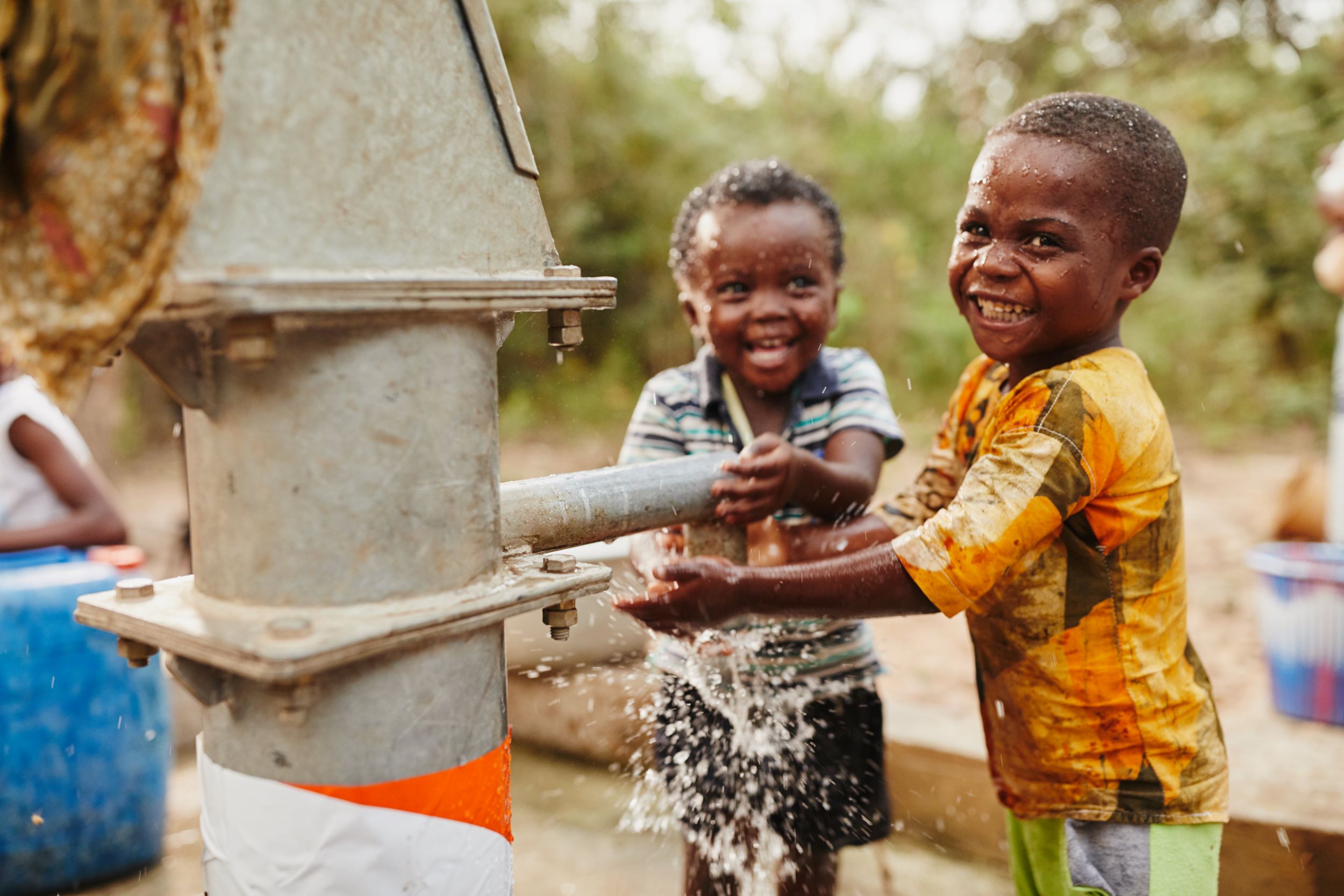 Two boys splashing in a community pump in Ghana 