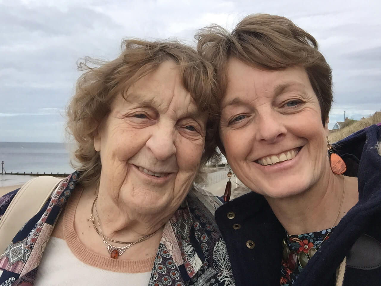 Two women in the UK smile, their heads resting against each other