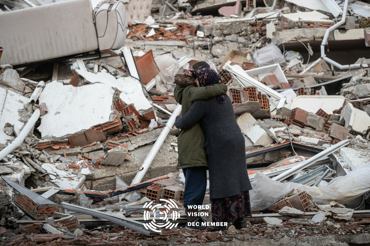 Women hug near a collapsed building in Turkey after one loses her brother in the devastating earthquake in February 2023.