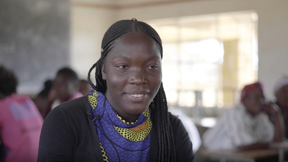 Girl in Zambia sits in a classroom and smile