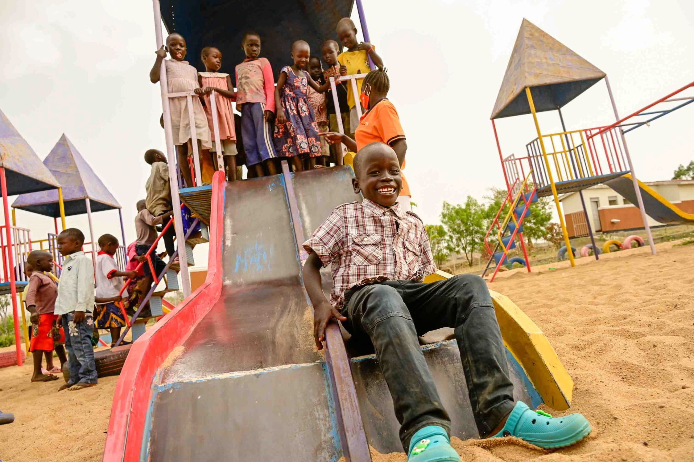 Children playing on a slide at a Child Friendly Space in Uganda
