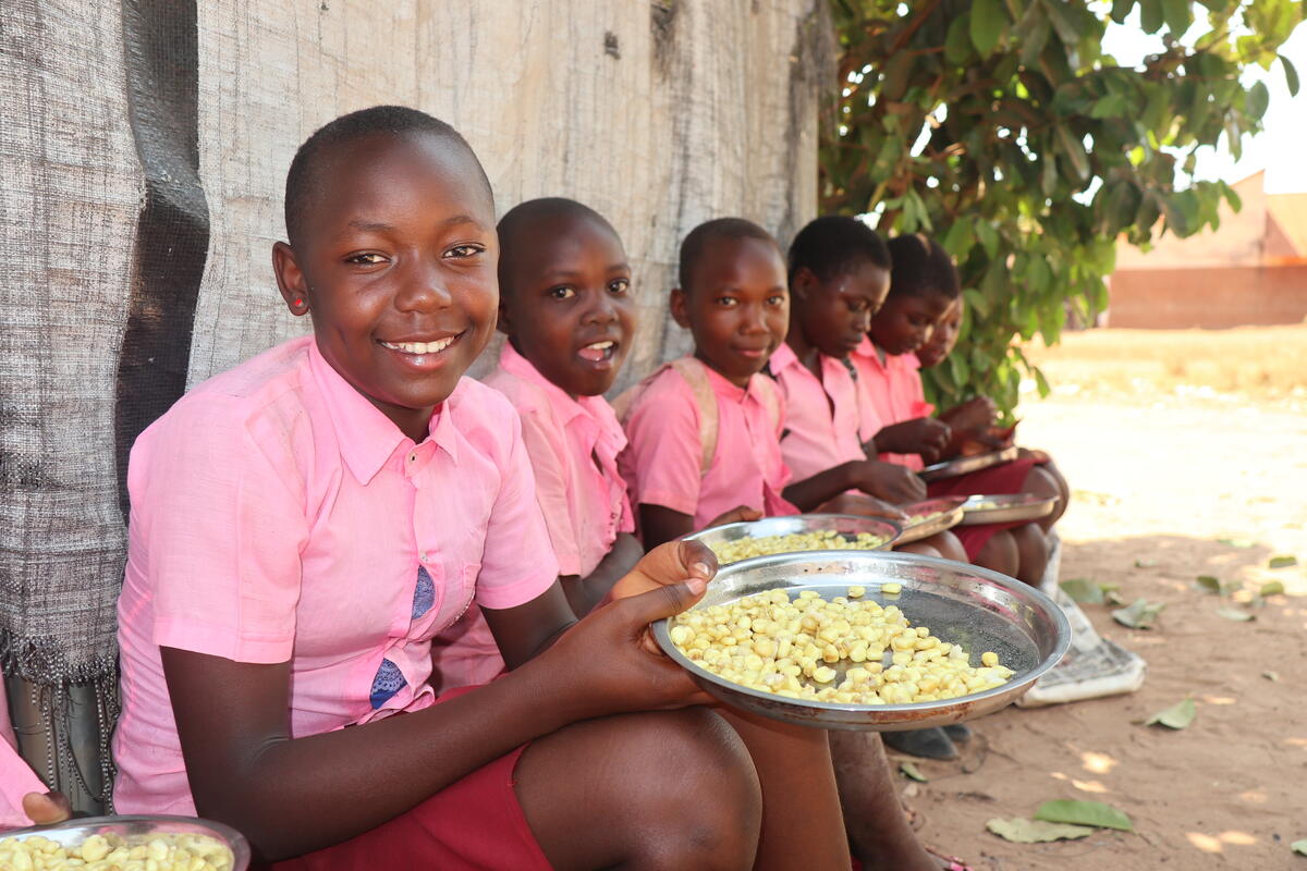 A family of four from Cambodia smiling at the camera with a large bowl of rice