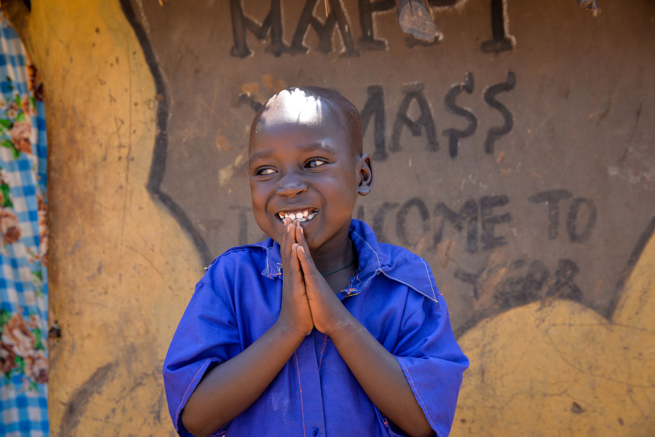 A boy in Uganda with his hands held together in prayer