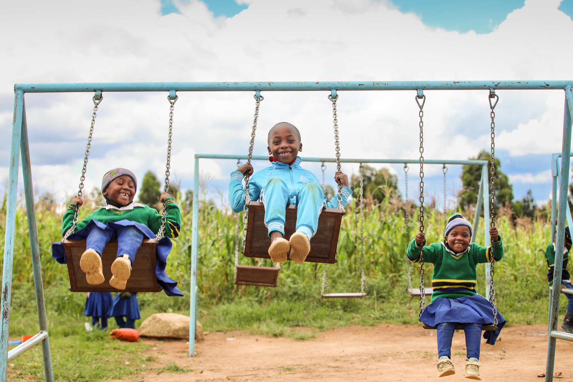 Three young boys enjoy playing on swings in Tanzania
