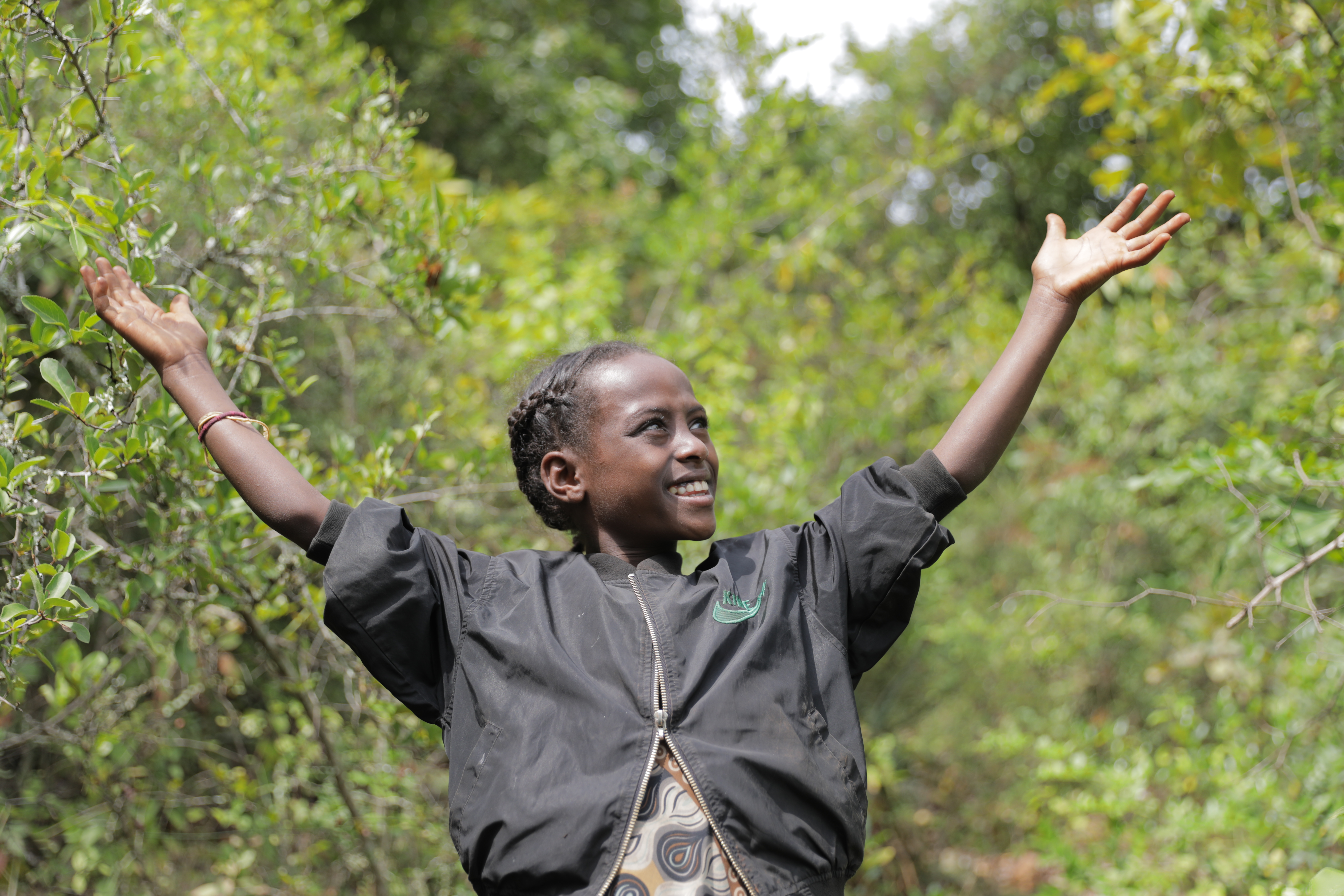 A young Ethiopian girl smiles with her arms outstretched