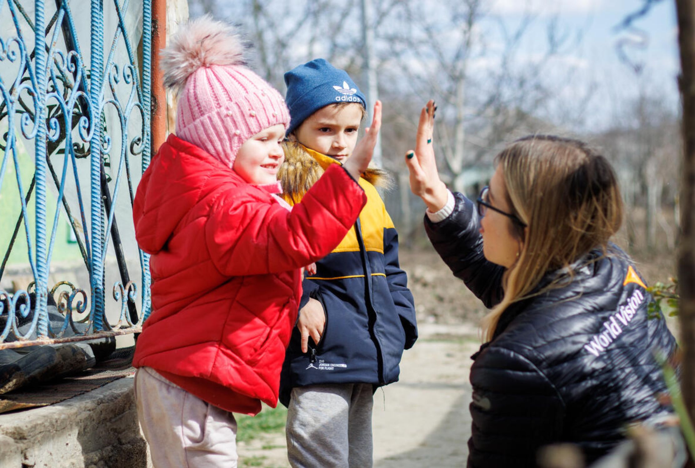 Two Ukrainian refugee children high-fiving World Vision staff 