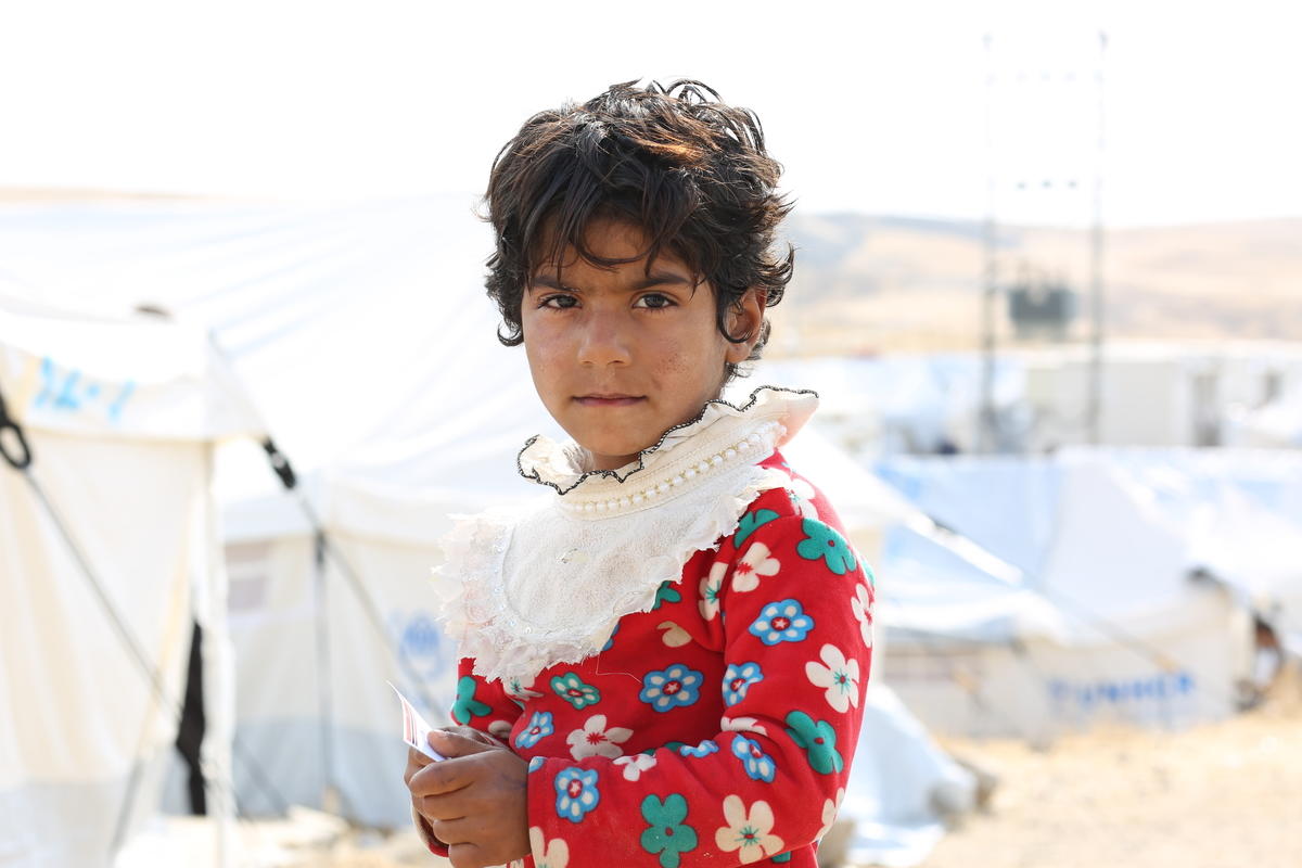 A young child from Syria stands amongst the tents in a refugee camp in Iraq