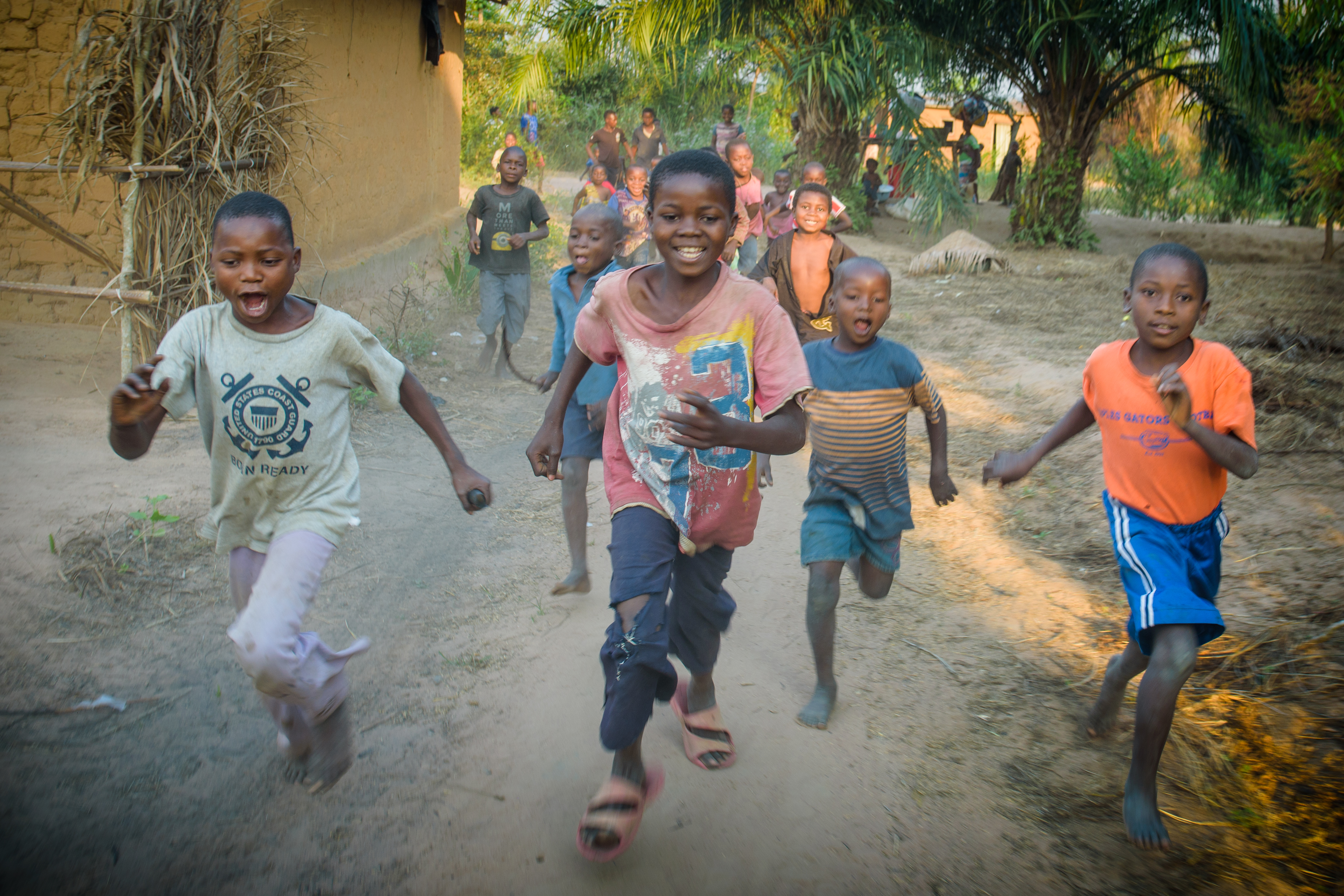 A group of children from the DRC running towards the camera with smiles on their faces