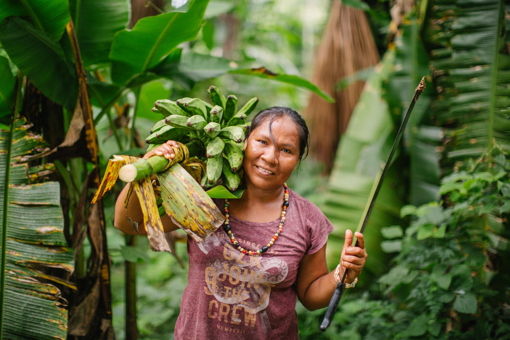 A woman in Peru holds bananas on her shoulder