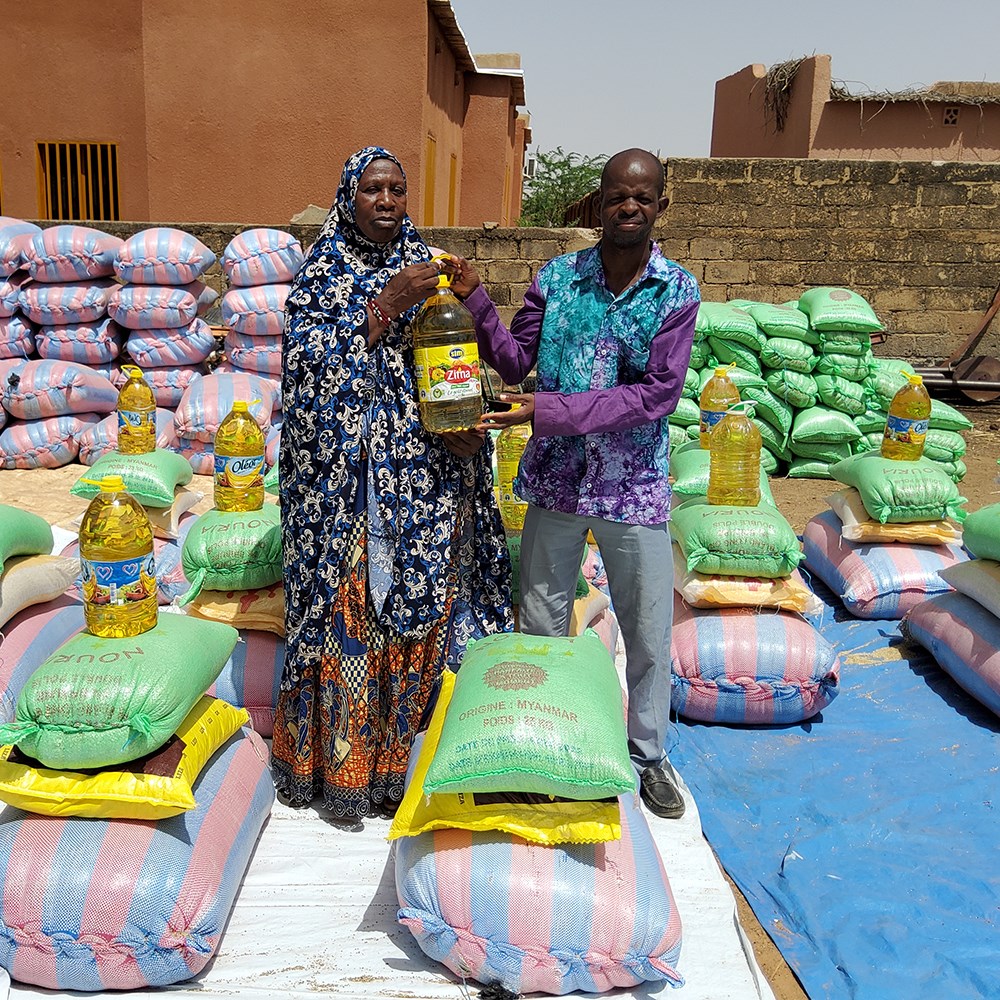 World Vision worker handing large bags of food to community